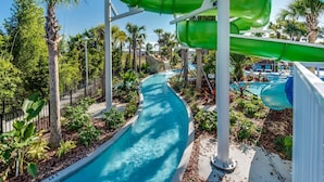 A water park with a winding pool, green and blue slides, palm trees, and a clear sky. - New Listing! Windsor Island, 10mi to Disney & 22mi to Universal - GRH813485 (Davenport)