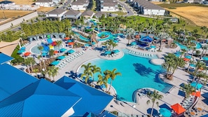 An aerial view of a resort with a large central pool, multiple water slides, and a variety of sun loungers and umbrellas. - New Listing! Windsor Island, 10mi to Disney & 22mi to Universal - GRH813485 (Davenport)