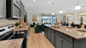 A modern kitchen with granite countertops, stainless steel appliances, and a large island. - New Listing! Windsor Island, 10mi to Disney & 22mi to Universal - GRH813485 (Davenport)