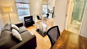 Una sala de estar moderna con sofá, televisor y comedor con mesa y sillas.