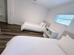 A bedroom with a large bed, a smaller bed, a nightstand, and a built-in shelving unit.