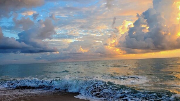 Una playa con olas y un cielo al atardecer.