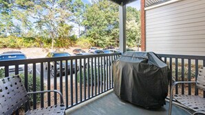 A covered outdoor area with metal chairs, a barbecue grill, and a view of parked cars and trees. - *Family Stay 2 minutes to downtown Sleeps 10 (Auburn)
