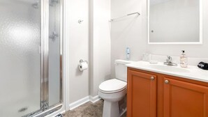 A bathroom with a glass shower door, a toilet, and a vanity with a mirror. - *Family Stay 2 minutes to downtown Sleeps 10 (Auburn)