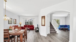 A spacious living area with a dining table, red and blue sofas, and a staircase leading to another level. - New Listing! Highlands Reserve Resort, 7mi to Disney & 17mi to Universal - FS379833 (Davenport)