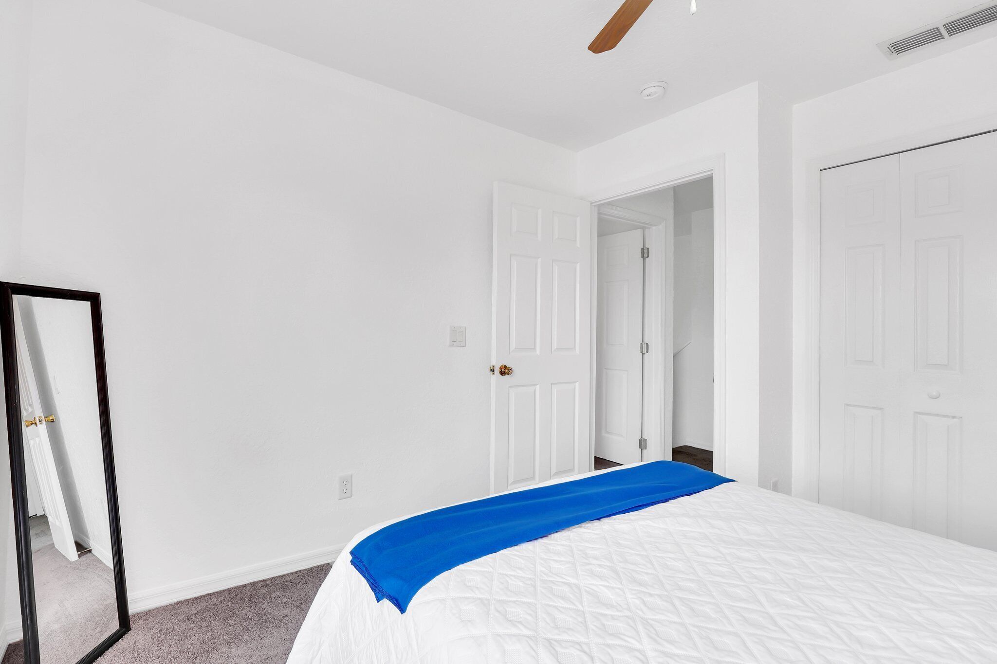 Une chambre à coucher avec un lit, des murs blancs et une porte.