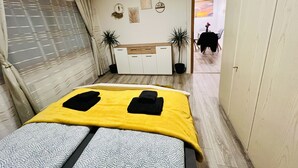 Un dormitorio con cama, un armario, un escritorio y dos plantas en macetas.