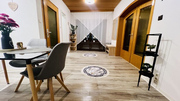 Un comedor con mesa y sillas de madera, una planta en maceta y una pequeña estatua.