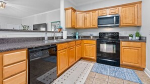 Une cuisine moderne avec des meubles en bois, un lave-vaisselle noir, un four à micro-ondes et un four traditionnel.