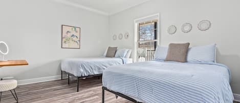 Een slaapkamer met twee bedden, een plafondventilator, een nachtkastje met spiegel en een klein krukje.