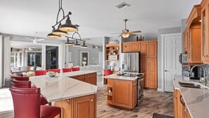 Una cocina amplia con armarios de madera, una isla grande y electrodomésticos modernos.