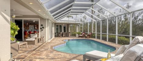 Una piscina exterior techada con sillones de descanso y un área de patio.