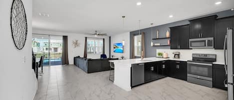 Una cocina moderna con armarios oscuros, encimera blanca y electrodomésticos de acero inoxidable.