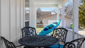 A covered porch with a table and chairs, a blue kayak, and a view of neighboring houses. - Lakefront House with Ping Pong, Pool Table, & Front Patio Stunning Views (Nevada)