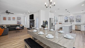 A modern kitchen with white cabinets, a wooden dining table set with white plates and glasses, and a chandelier. - Lakefront House with Ping Pong, Pool Table, & Front Patio Stunning Views (Nevada)