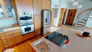 Een moderne keuken met roestvrijstalen apparatuur, houten kastjes en een centraal keukenblok met een spoelbak.