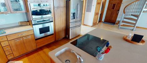 A modern kitchen with stainless steel appliances, wooden cabinets, and a central island with a sink.