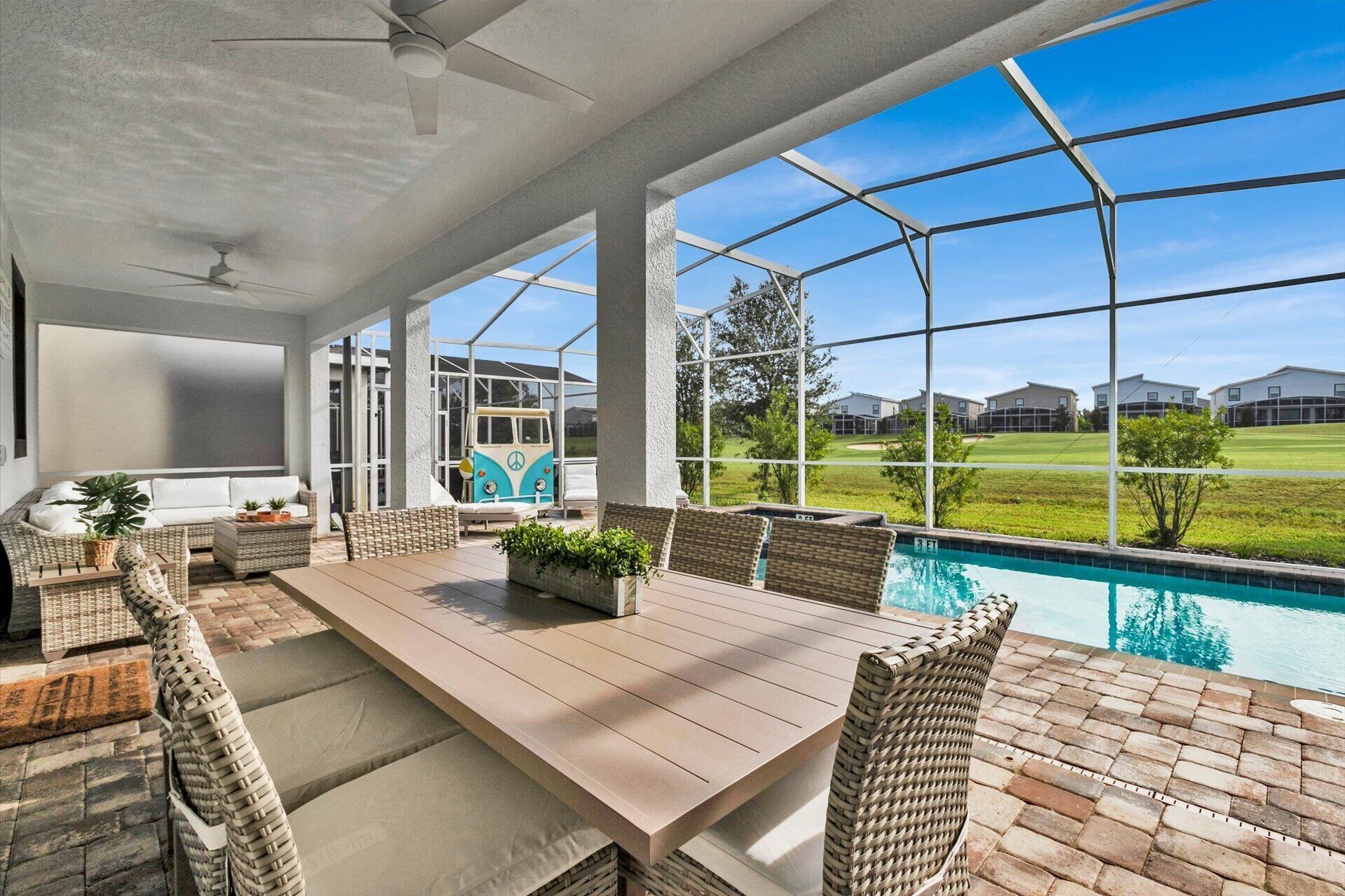 A covered patio with a pool, wicker furniture, and a view of a residential area.