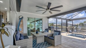 A covered outdoor patio with wicker furniture, a ceiling fan, and a view of a swimming pool and houses. - New Listing! Charlotte Harbor Area Resort, 120mi to Disney & 134mi to Universal - GRH595427 (Punta Gorda)