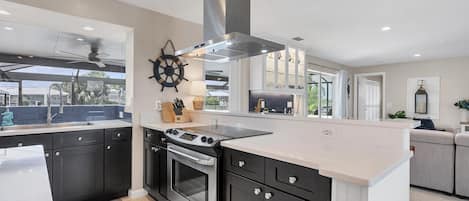 A modern kitchen with dark cabinets, a stainless steel range, and a large island.