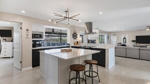 A modern kitchen with a large island, bar stools, and a ceiling fan. - New Listing! Charlotte Harbor Area Resort, 120mi to Disney & 134mi to Universal - GRH595427 (Punta Gorda)