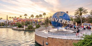 Universal Studios sign stands proudly on a circular structure surrounded by water and lush palm trees.