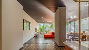 Ein modernes Interieur mit einem gemusterten Boden, einem roten Sofa und einer Essecke mit Holzmöbeln.