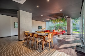 A modern interior with a dining area, a sofa, and a large window.