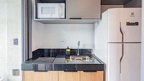 Eine kleine Küchenzeile mit Mikrowelle, Spüle und Kühlschrank.