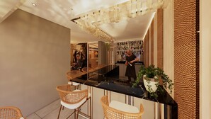 Zona de bar moderna con una encimera negra, sillas de mimbre y una barra llena de botellas.