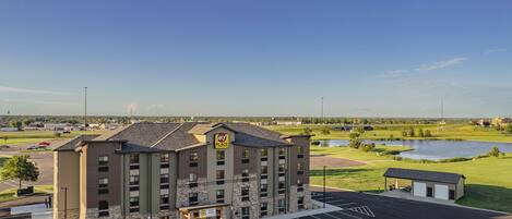 A multi-story hotel with a stone facade and a parking lot in front.