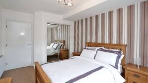 A bedroom with a wooden bed, a nightstand, a mirror, and striped curtains.