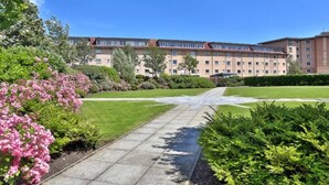 A large building with multiple floors, surrounded by well-maintained lawns and a central pathway.