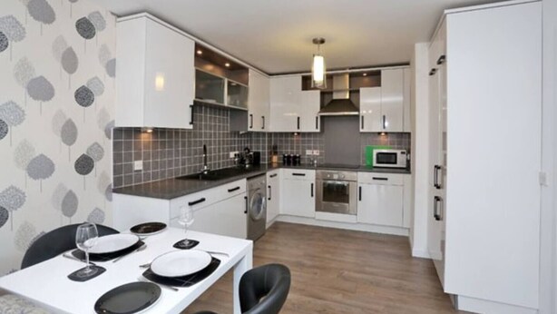 A compact kitchen with white cabinets, a microwave, and a dining area with a table set for two.