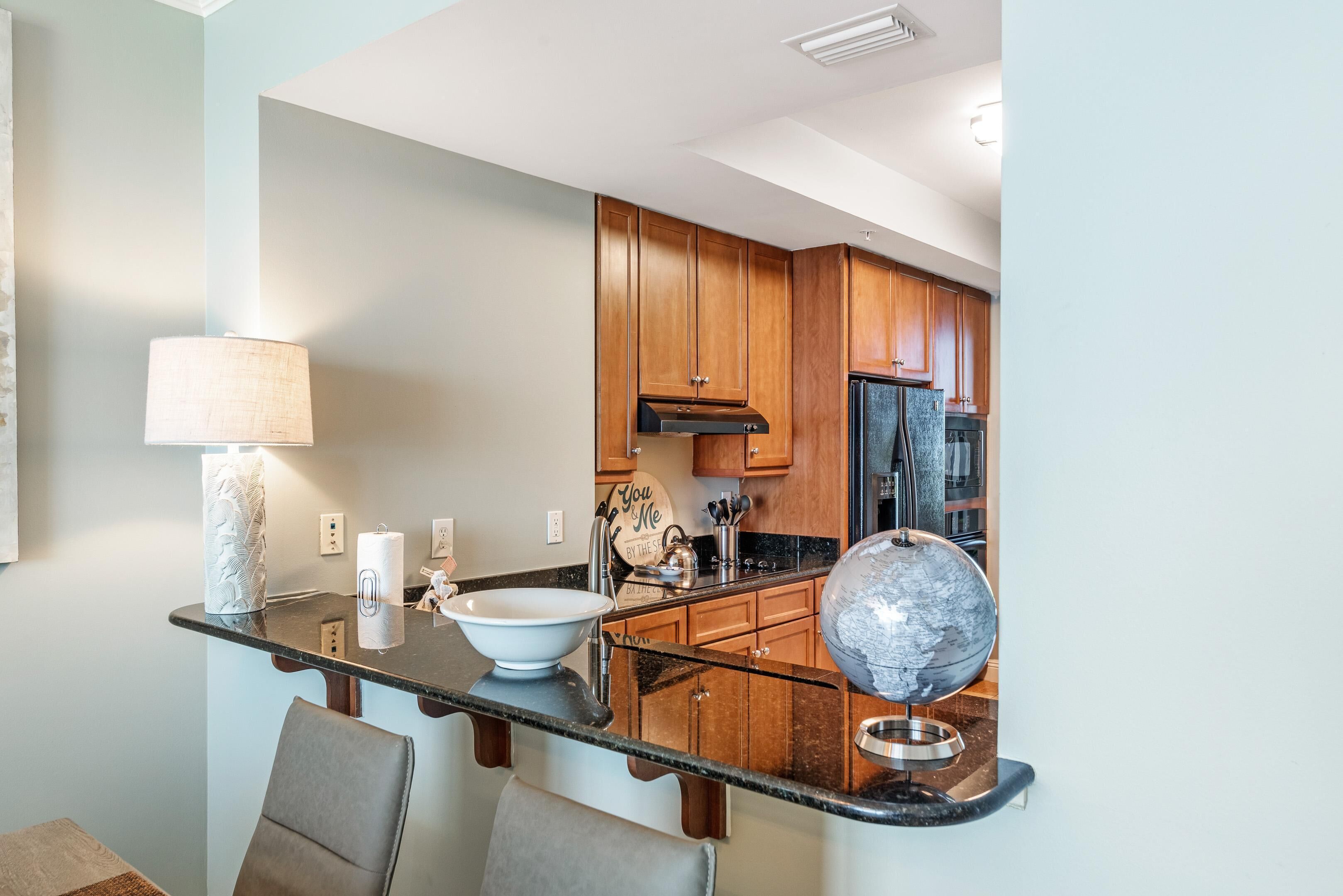A modern kitchen with wooden cabinets, a black countertop, and a globe.