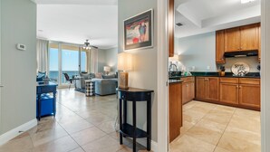 Amplia sala de estar con vistas al exterior, una cocina con armarios de madera y un comedor con mesa y sillas.