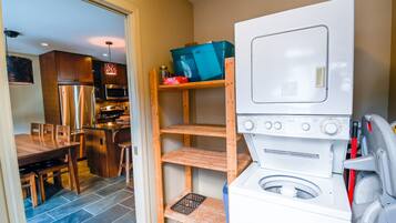 Une cuisine compacte dotée d’un lave-linge et d’un sèche-linge intégrés, de meubles en bois et d’un coin repas avec une table et des chaises.