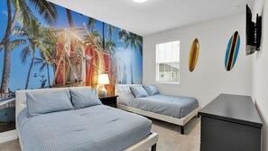 Une chambre avec deux lits, une fresque représentant un paysage tropical et des planches de surf accrochées au mur.