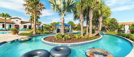 A swimming pool with three inflatable rings, palm trees, and a gazebo.