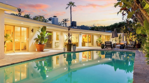 A modern house with a swimming pool, potted plants, and a patio area.