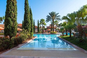 A swimming pool surrounded by tall cypress trees and palm trees, with a clear blue sky. - New Listing! Tuscana Resort, 11mi to Disney & 18mi to Universal - FS381569 (Davenport)