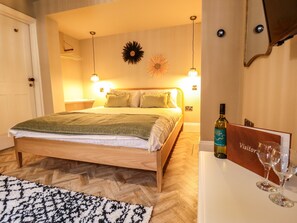 A neatly arranged bedroom with a bed, bedside lamps, and a bottle of wine on a table. - 17 Union Road Basement (Lincoln)