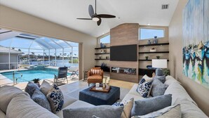 Un salón amplio con un sofá grande, chimenea y vistas a la piscina.