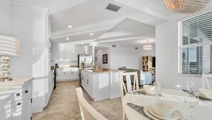 A spacious kitchen with white cabinetry, a central island, and a dining area with a table set for two. - New Listing! Charlotte Harbor Area Resort, 120mi to Disney & 134mi to Universal - GRH573595 (Punta Gorda)