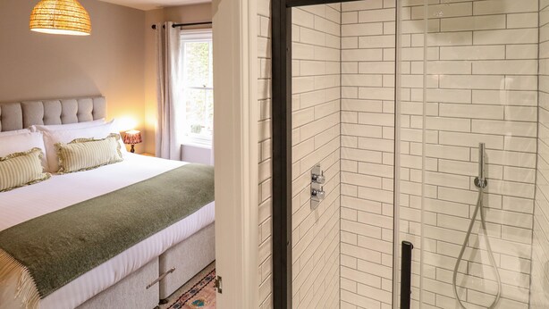 A hotel room with a bed, a shower, and a hanging light fixture. - 17 Union Road House (Lincoln)