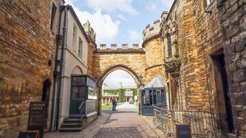 A cobblestone street leading to a historic building with an archway.