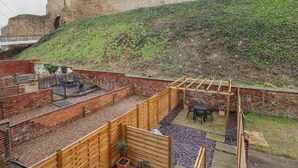 A courtyard with a brick wall, wooden pergola, and outdoor seating area. - 17 Union Road House (Lincoln)