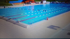 Una piscina con múltiples carriles, un tobogán acuático y una torre de socorristas.