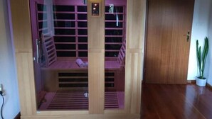 Una sauna con revestimiento de madera, un panel de control y un banco en el interior.