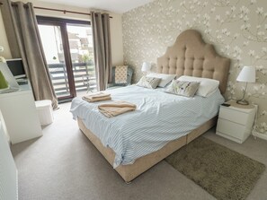 A bedroom with a bed, bedside tables, a lamp, and a view of the outside.
